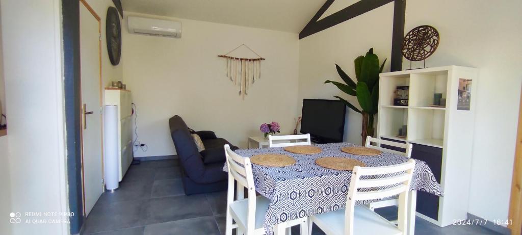a room with a table with chairs and a kitchen at Maison climatisée proche du lac in Sanguinet