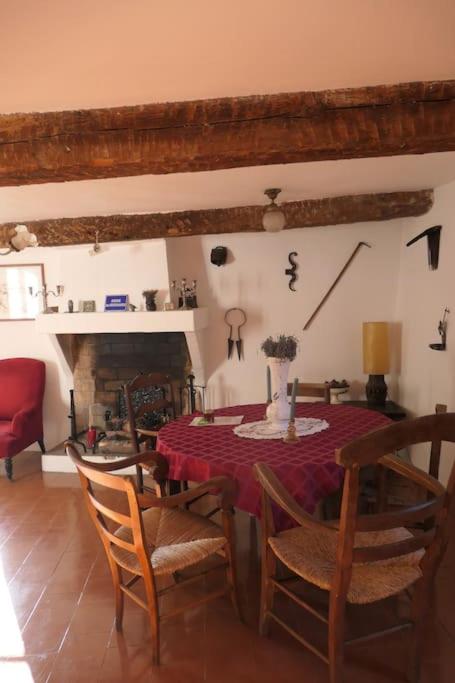 une salle à manger avec une table et des chaises et une cheminée dans l'établissement Le Baguier, maison de caractère dans hameau typique provençal, à Seillans