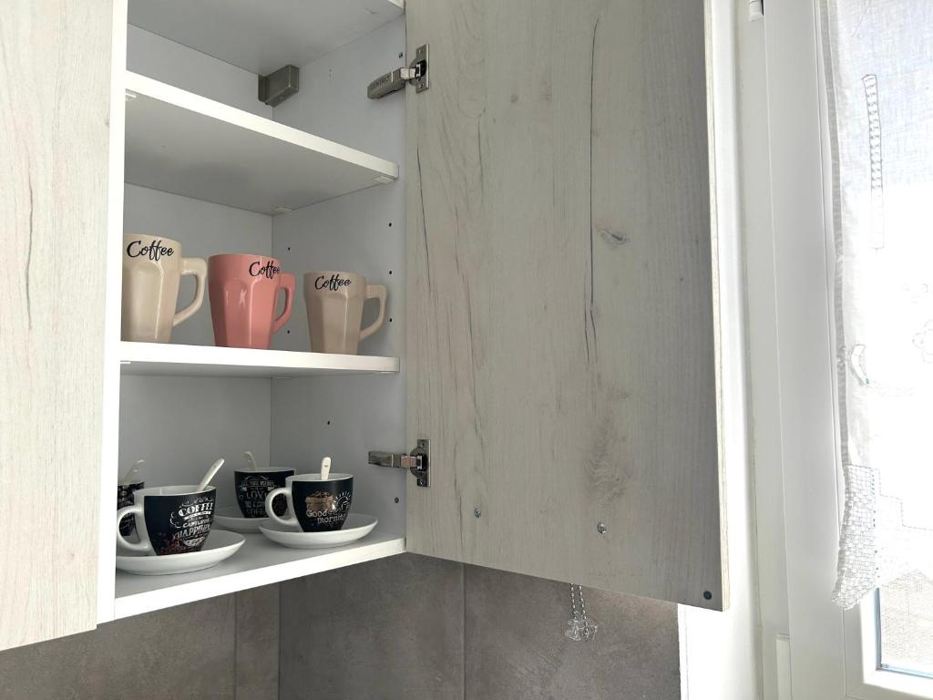 a cupboard with cups and mugs in it at Antiparos Diamond in Antiparos Town