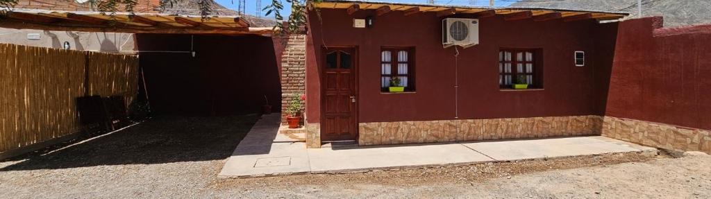 a red house with a red door and a fence at Cabaña KUYAY in Purmamarca