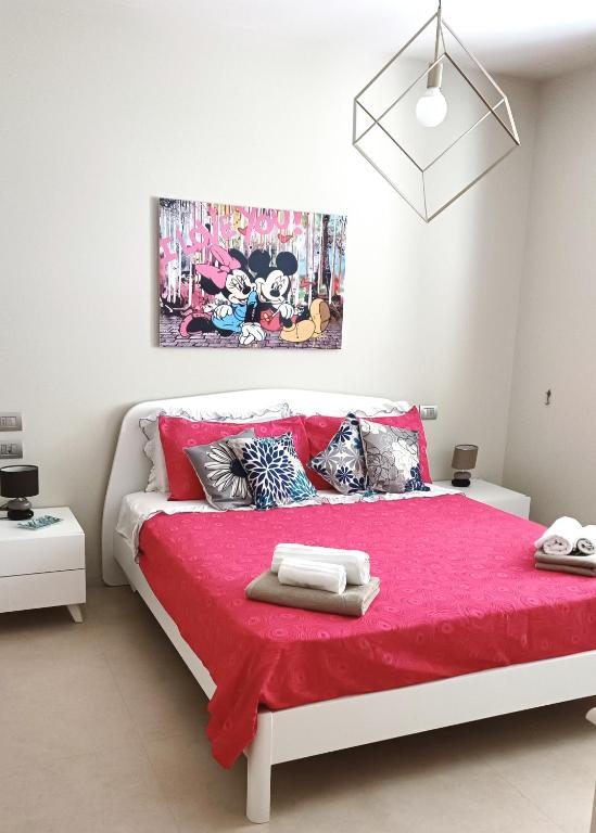 una camera con un letto rosa e una coperta rossa di Dody's Home a Otranto