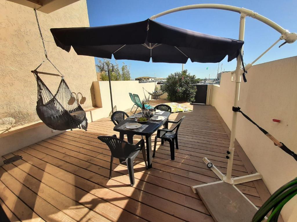 un patio avec une table, des chaises et un parasol dans l'établissement MAGNIFIQUE Pépite au bord de l eau, à Martigues