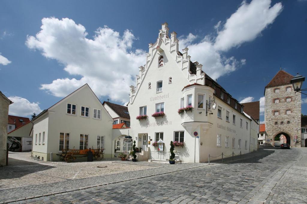 ein großes weißes Gebäude mit Blumen an den Fenstern in der Unterkunft Landhotel Weißer Hahn in Wemding