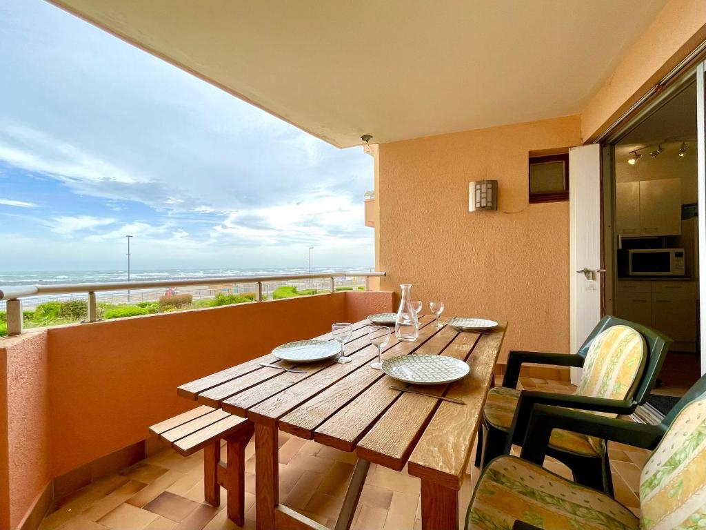 une table en bois sur un balcon avec vue sur l'océan dans l'établissement Appartement T3 à Sète face à la mer avec parking privé, proche plage et commerces - FR-1-338-587, à Sète