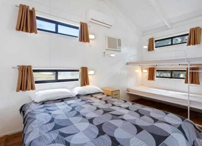ein Schlafzimmer mit einem großen Bett und zwei Fenstern in der Unterkunft South Goulburn Caravan Park in Goulburn