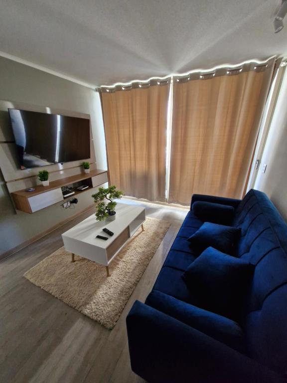 a living room with a blue couch and a tv at Departamento edificio rotterdam amoblado in Iquique
