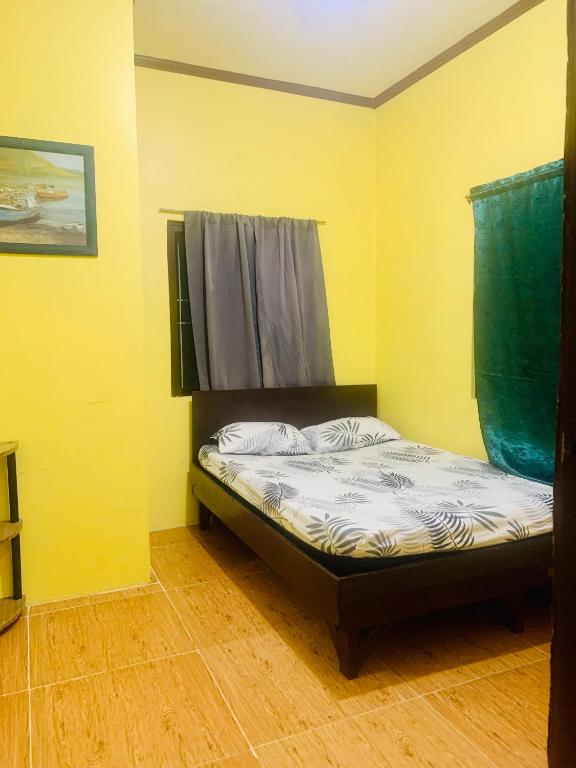 a small bed in a room with yellow walls at Perlies Inn Balcony House in Tanay