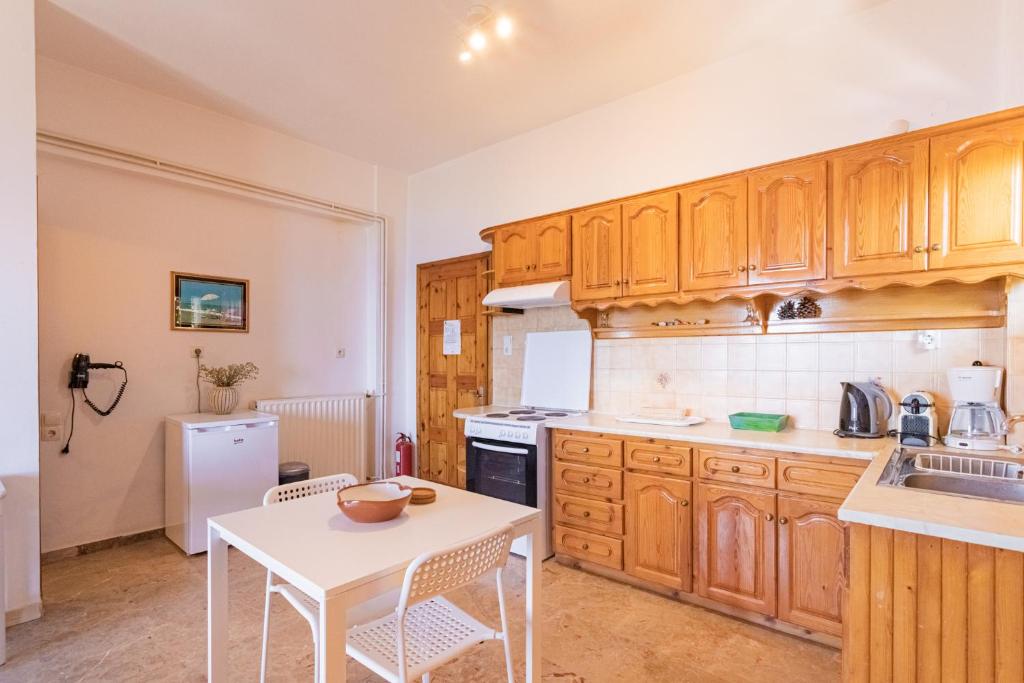 a kitchen with wooden cabinets and a white table at Dimitra's Studios in Stoupa