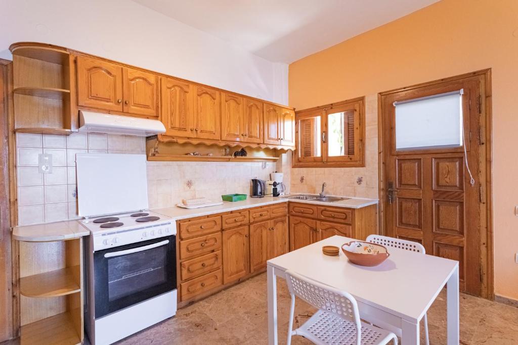 a kitchen with wooden cabinets and a white table at Dimitra's Studios in Stoupa