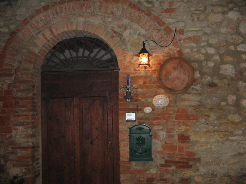 a brick wall with a door and a light and a lantern at La Corte di Ardengo in Civitella Marittima