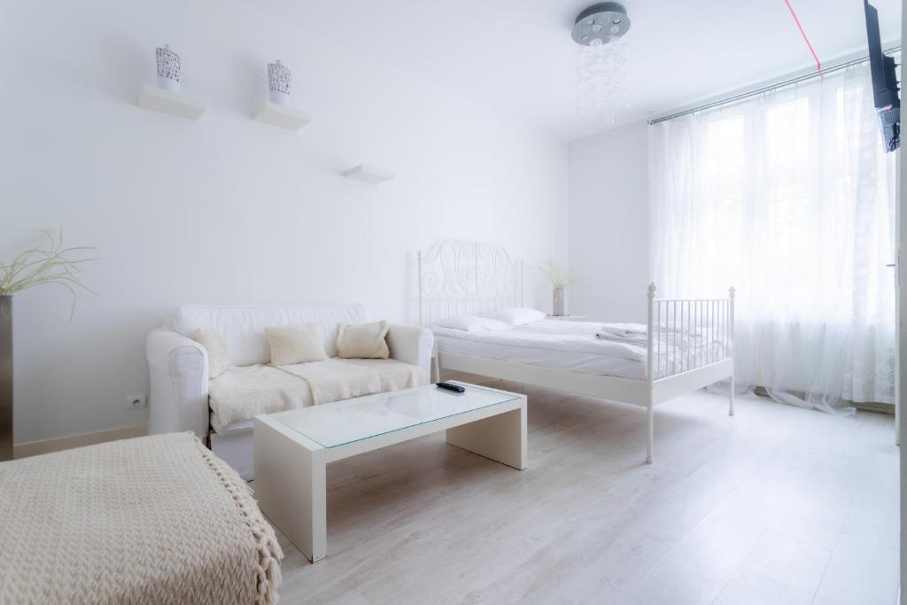 a white living room with a couch and a crib at Villa Superiq Victus Sopot Walk to the Pier by Noclegi Renters in Sopot