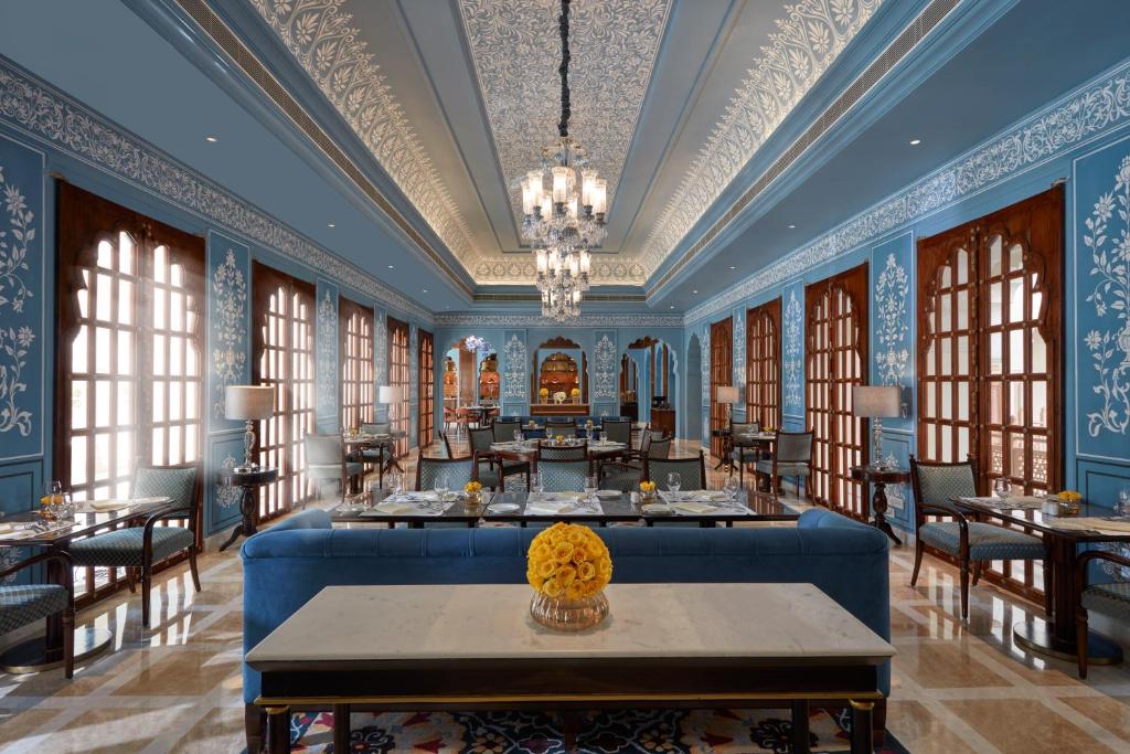 a dining room with blue walls and tables and windows at Mementos by ITC Hotels Jaipur in Jaipur