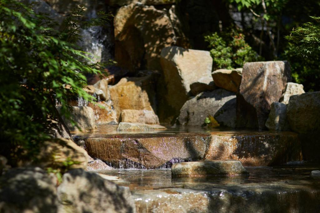 a waterfall in a garden with rocks and trees at THE HOTEL SANRAKU KANAZAWA 21th December 2022 OPEN in Kanazawa