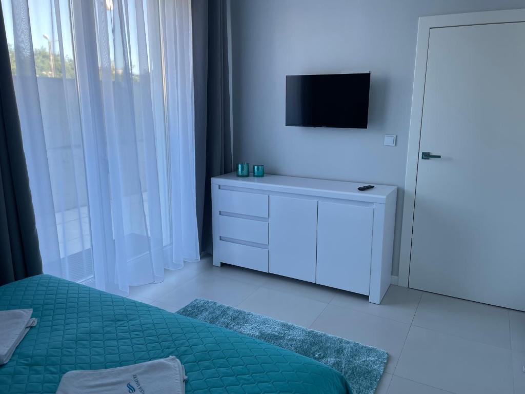 Televízia a/alebo spoločenská miestnosť v ubytovaní Apartamenty AQUA MAZURY