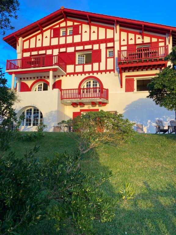 une grande maison avec balcon rouge sur une colline dans l'établissement VILLA ETCHE CAROLA BIDART - Le peintre Appartement 1er Étage, à Bidart