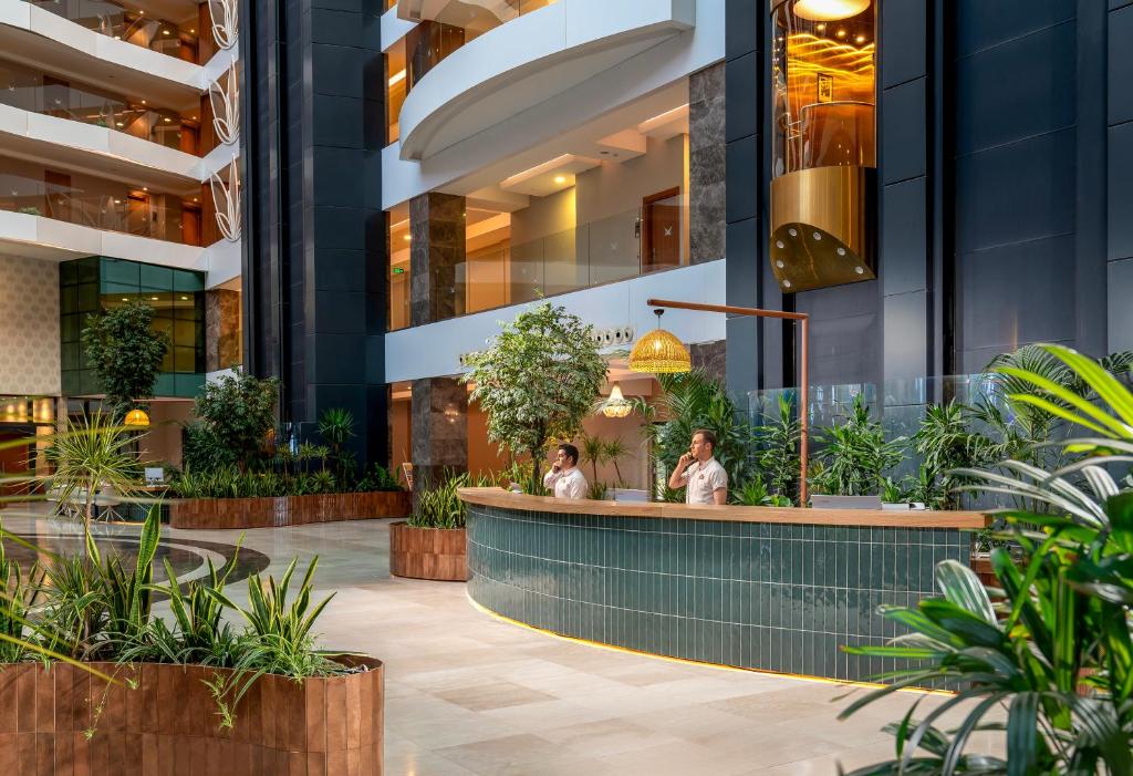 a lobby of a building with a bar and plants at Liberty Kuşadası in Kusadası