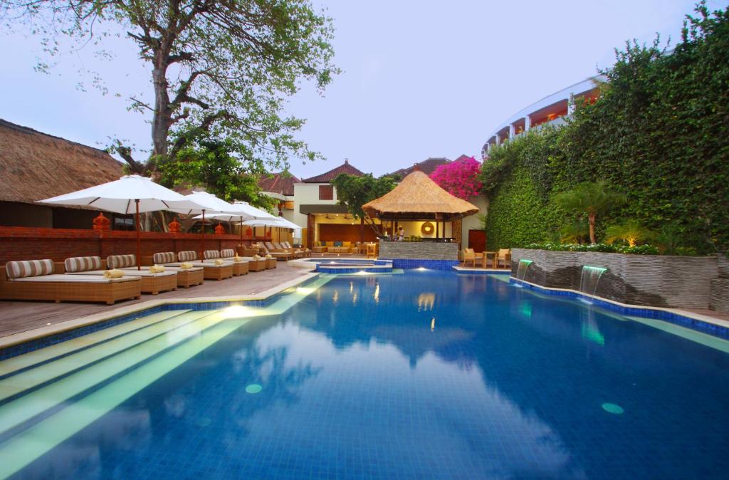a swimming pool with chairs and umbrellas at a resort at AlamKulkul Boutique Resort in Kuta