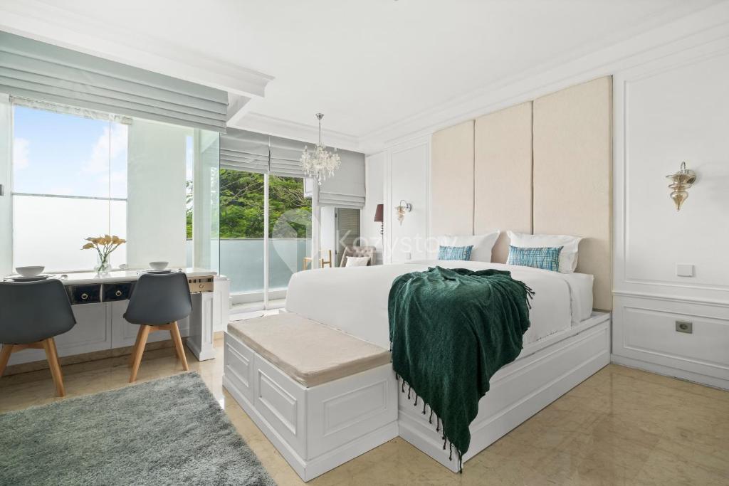 a white bedroom with a bed and a desk at Askara by Kozystay - Ciumbuleuit in Bandung