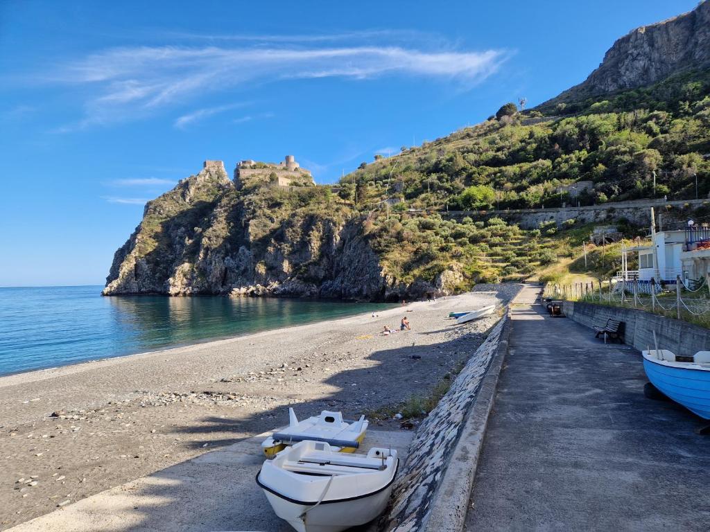 a beach with boats on the sand and a mountain at Casa vacanze STEVIA in Santa Margherita-Sant'Alessio Siculo