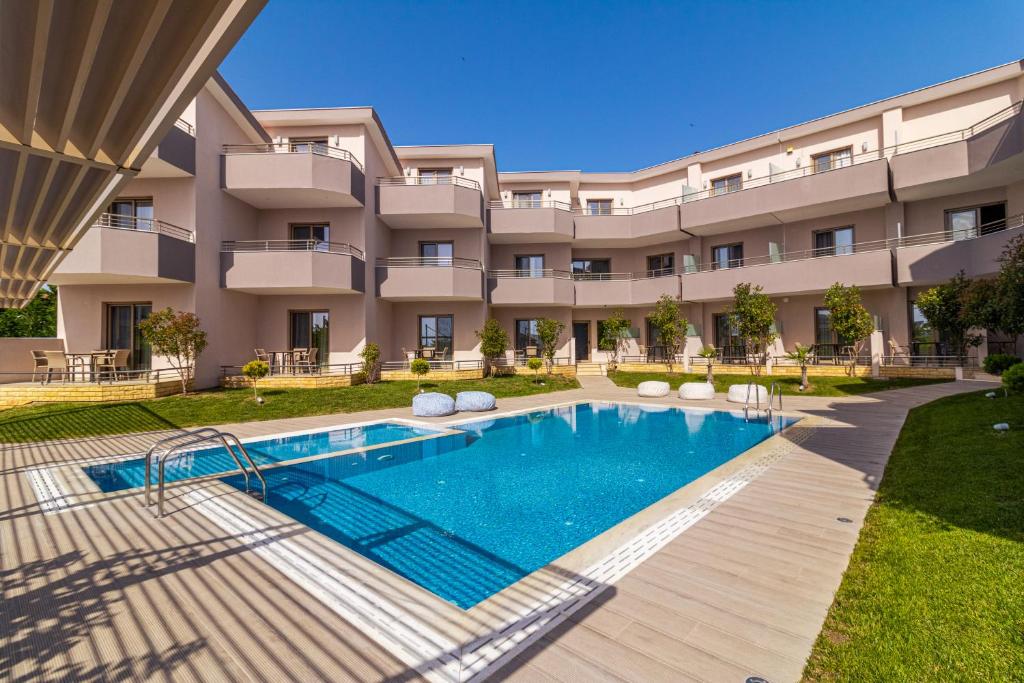 an apartment building with a swimming pool in front of it at Aria Garden Suites in Nikiti
