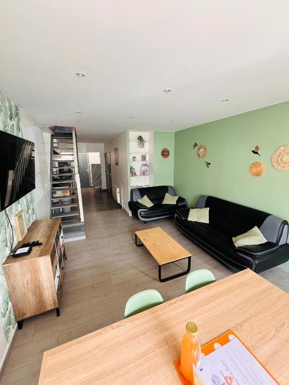 - un salon avec des canapés noirs et une table dans l'établissement La Maison du Bastion - Gravelines centre, à Gravelines