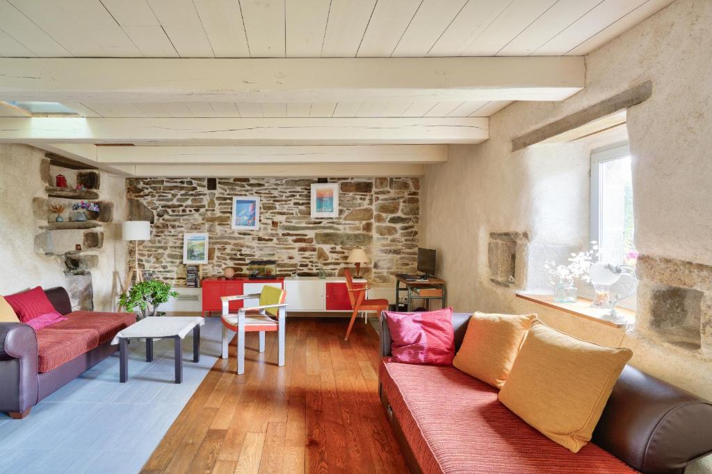 un salon avec un canapé et un mur en pierre dans l'établissement 1km de la plage, maison de charme pour 6, à Plovan