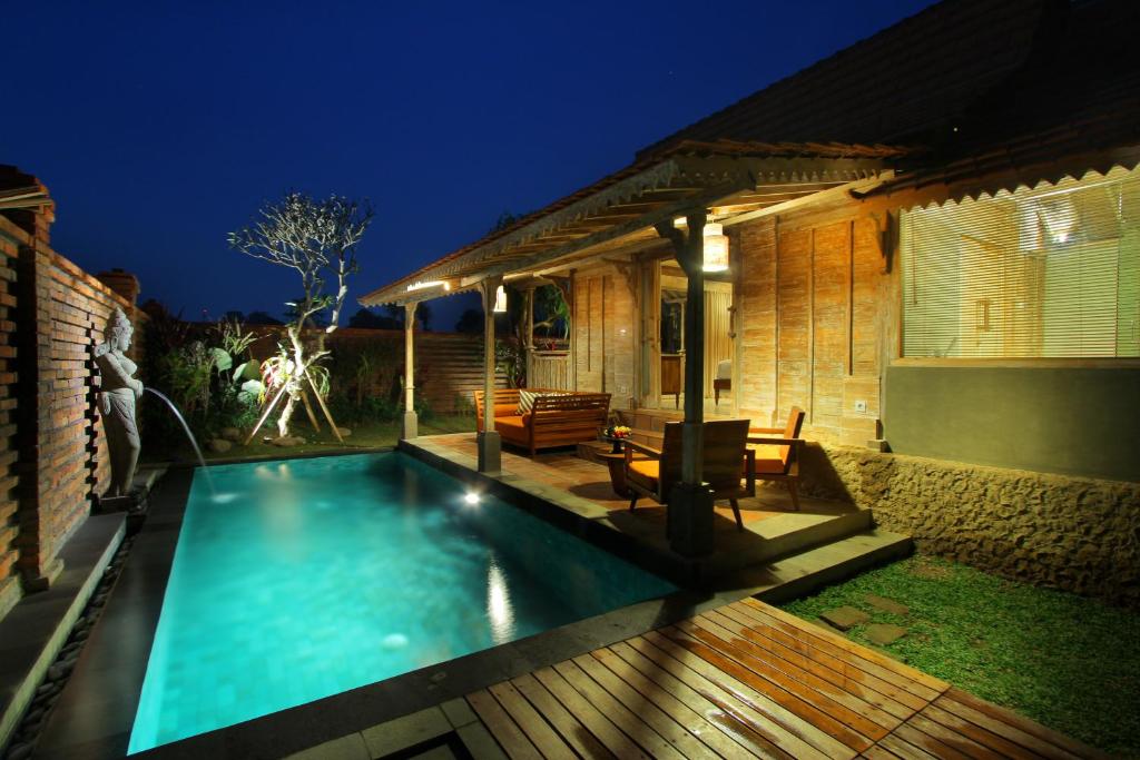 a swimming pool in front of a house at night at Suarti Boutique Village in Ubud