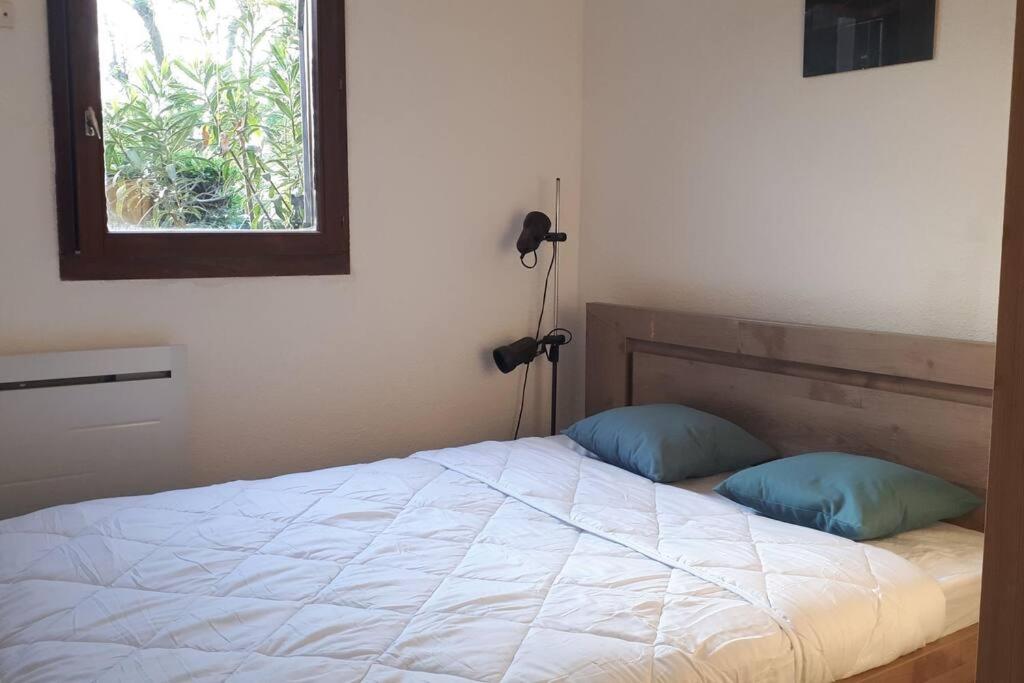 - une chambre avec un lit avec deux oreillers et une fenêtre dans l'établissement Magnifique petite maisonnette climatisée avec parking privatif, au Barcarès