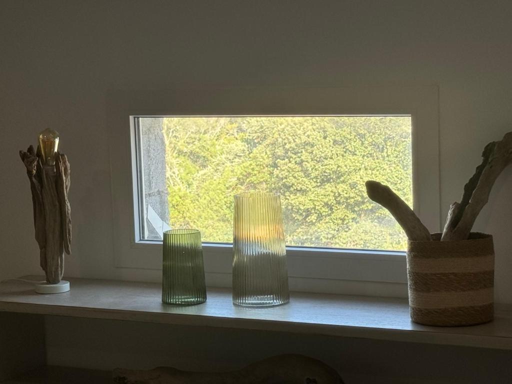 trois vases verts posés sur un rebord de fenêtre dans l'établissement Jolie maison au cœur du maquis, à Grosseto-Prugna