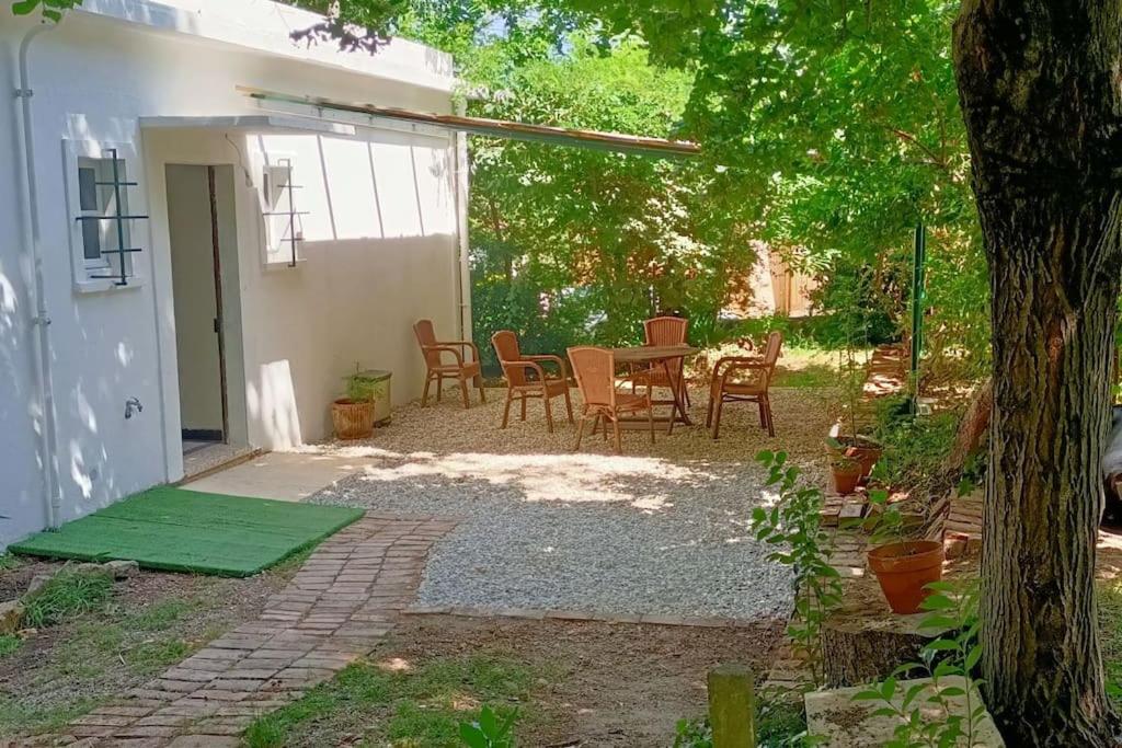 un patio avec une table et des chaises dans une cour dans l'établissement La Colline aux Oiseaux, La tranquillité des bois, à Molières-sur-Cèze