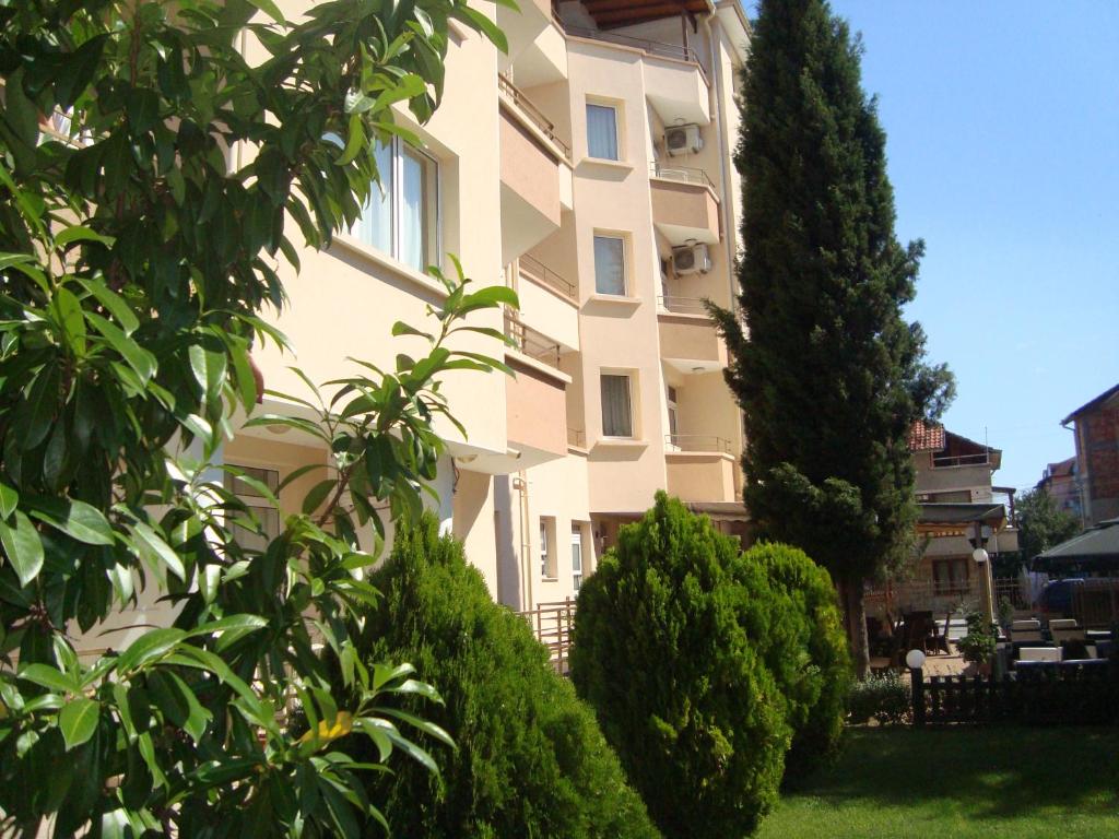 un gran edificio blanco con árboles delante de él en Hotel Astra en Ravda