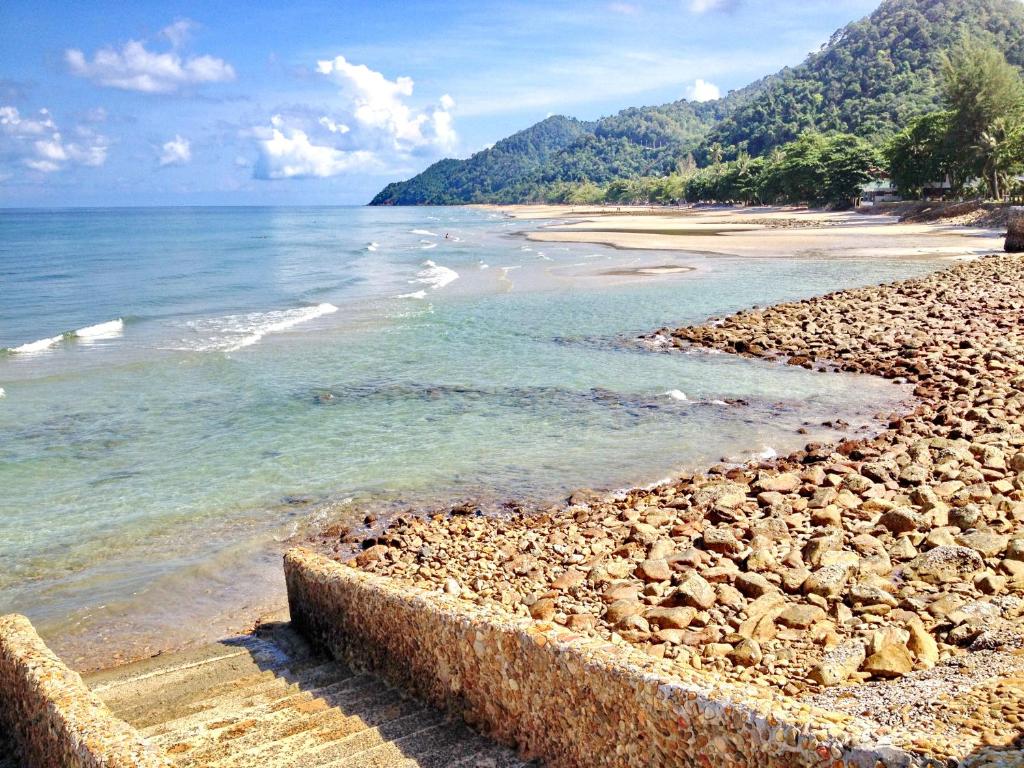 a rocky beach with the ocean and mountains in the background at Chang Buri Resort & Koh Chang Hillside in Ko Chang
