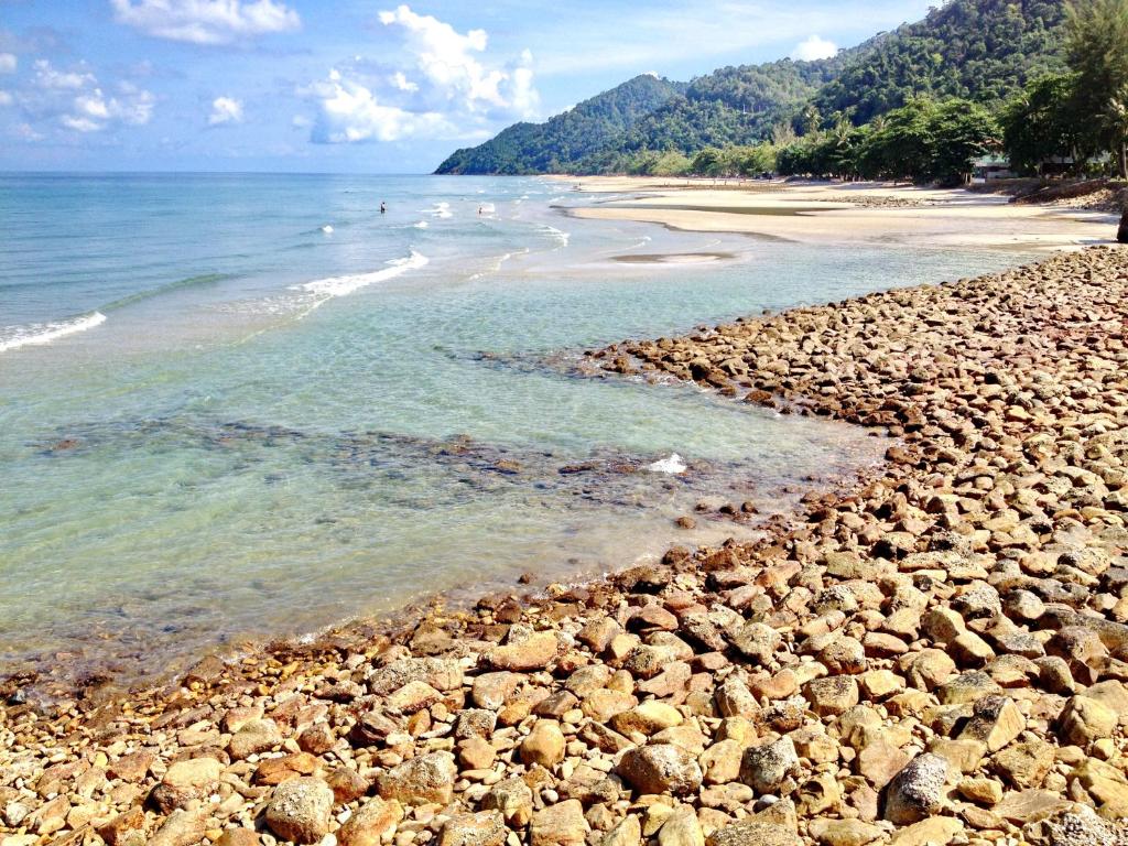 a rocky beach with people swimming in the water at Chang Buri Resort & Koh Chang Hillside in Ko Chang