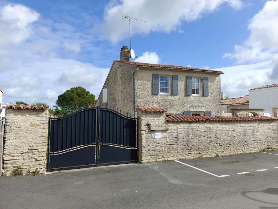 a house with a black gate in a parking lot at Belle maison familiale près de La Rochelle in Ferrières