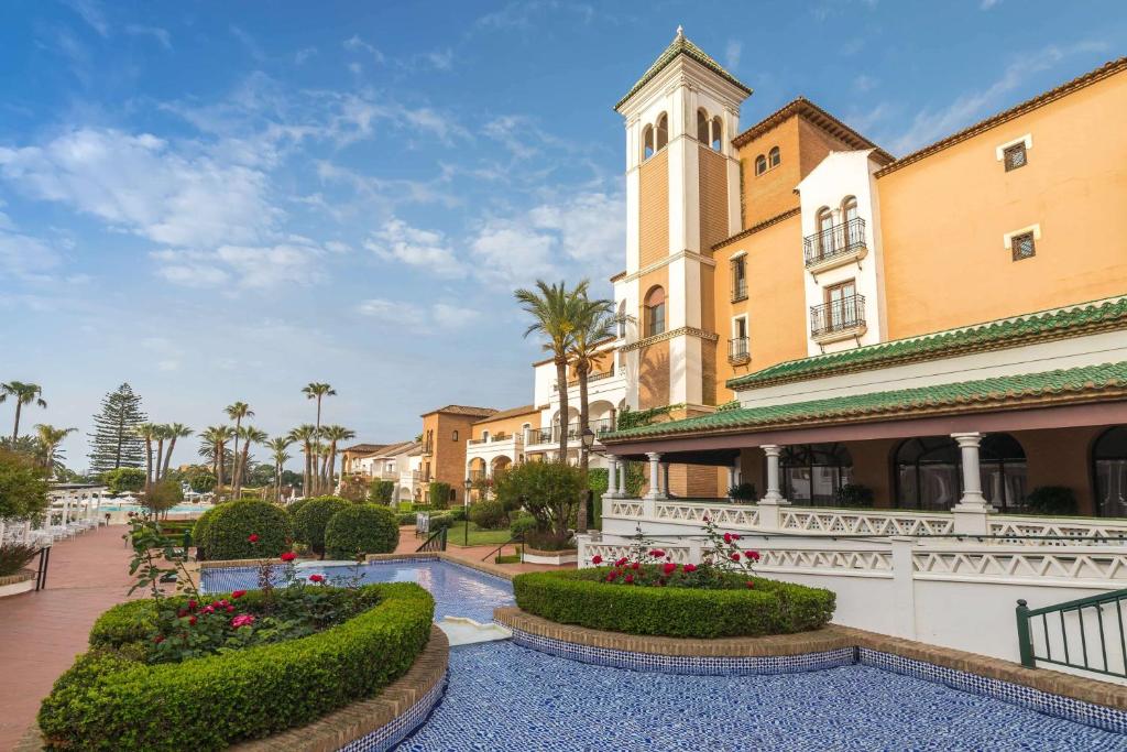 a building with a clock tower and a courtyard at Barceló Isla Canela in Isla Canela