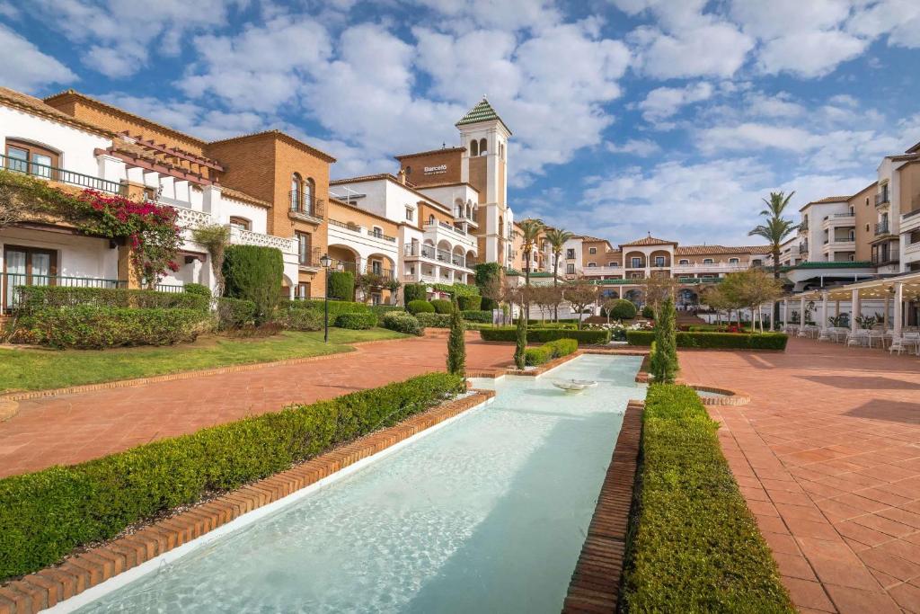 a walkway in the middle of a courtyard with buildings at Barceló Isla Canela in Isla Canela