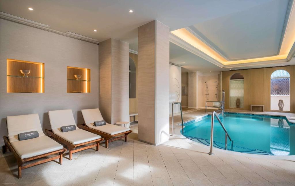 a pool in a hotel room with chairs and a swimming pool at Barceló Isla Canela in Isla Canela