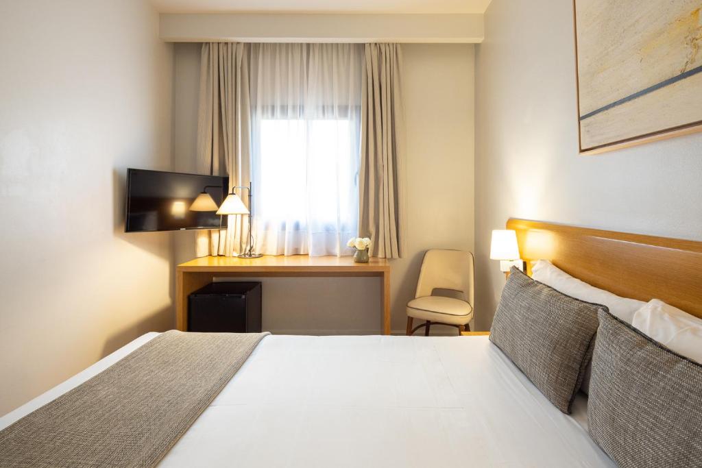 a hotel room with a bed and a desk and a window at Arc La Rambla in Barcelona