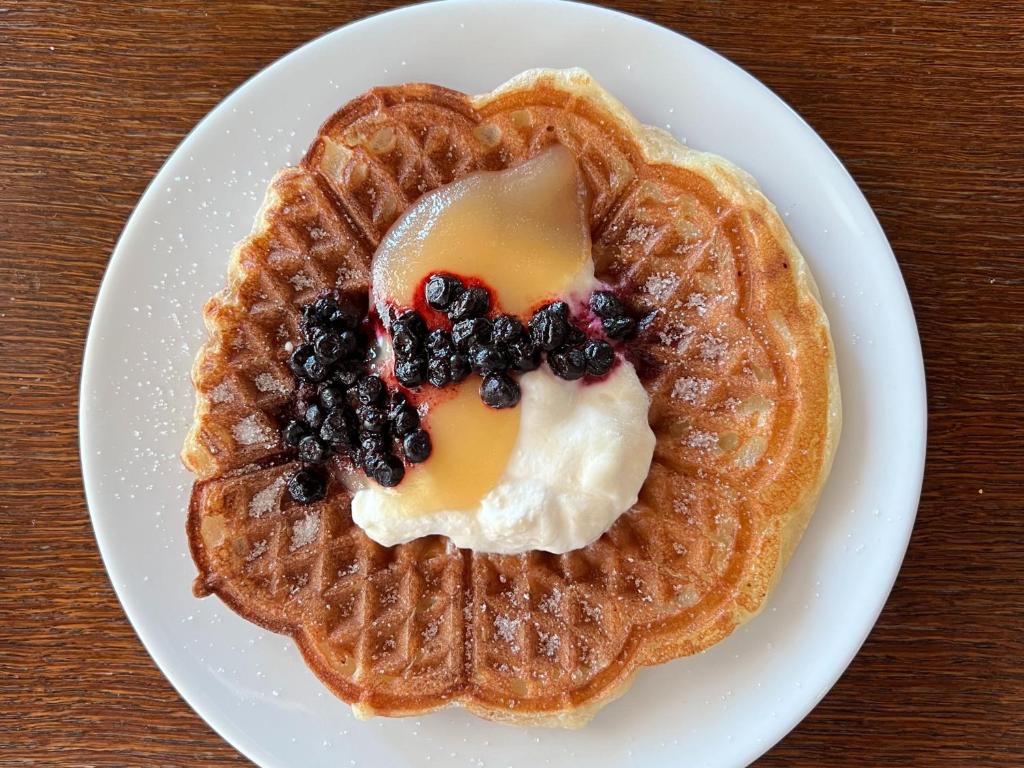a plate of waffles with syrup and berries on it at Santa's Hotel Santa Claus in Rovaniemi