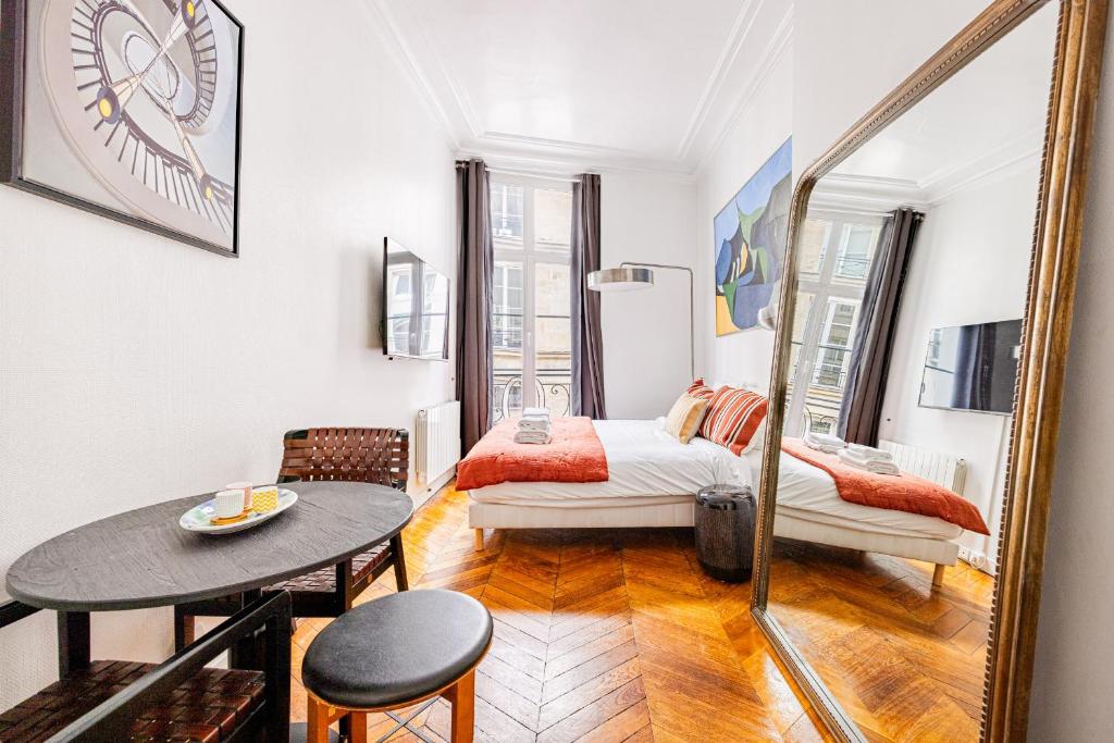 une chambre avec un lit, une table et un miroir dans l'établissement Luminous Studio Oasis Steps from The Louvre, à Paris