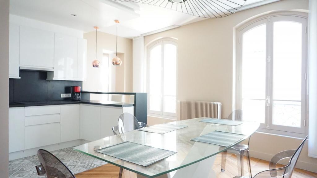 - une cuisine avec une table en verre et des chaises dans l'établissement Rue Poncelet - Paris 17, à Paris