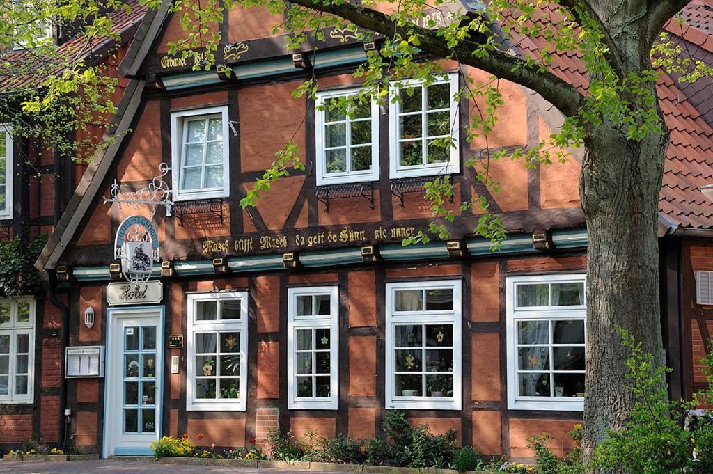 a wooden building with white windows and a tree at Hotel St. Georg Garni in Celle