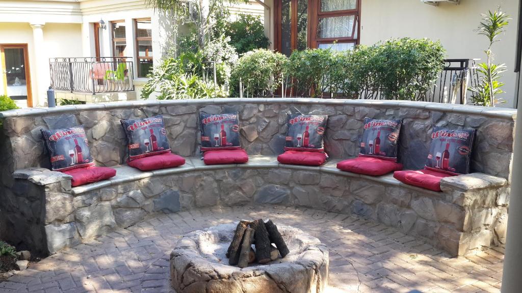 a stone bench with red cushions and a fire pit at Eagle Rock Executive Guest House in Kempton Park