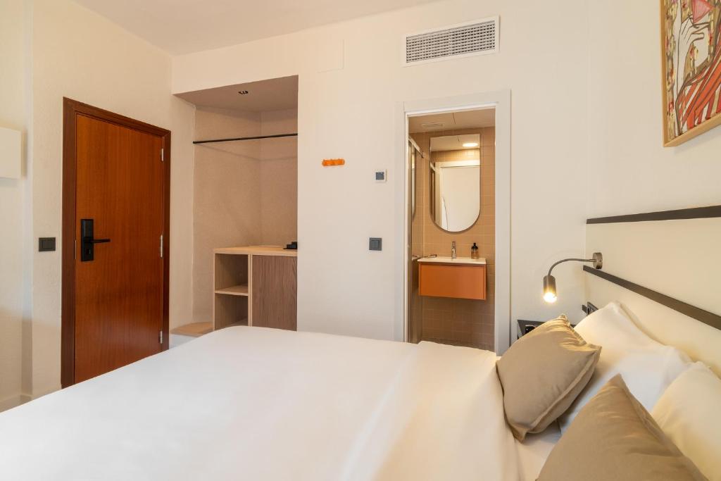 a bedroom with a white bed and a bathroom at Hotel Robson - Smart Hotel in Lloret de Mar