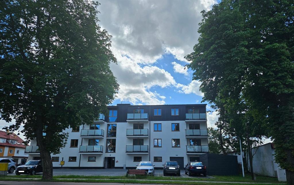 a white building with cars parked in front of it at Apartamenty przy Dworku in Człuchów