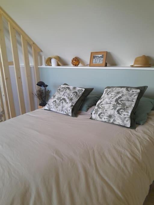 un lit blanc avec deux oreillers dessus dans l'établissement Petite maison bord de mer, à Barneville-Carteret
