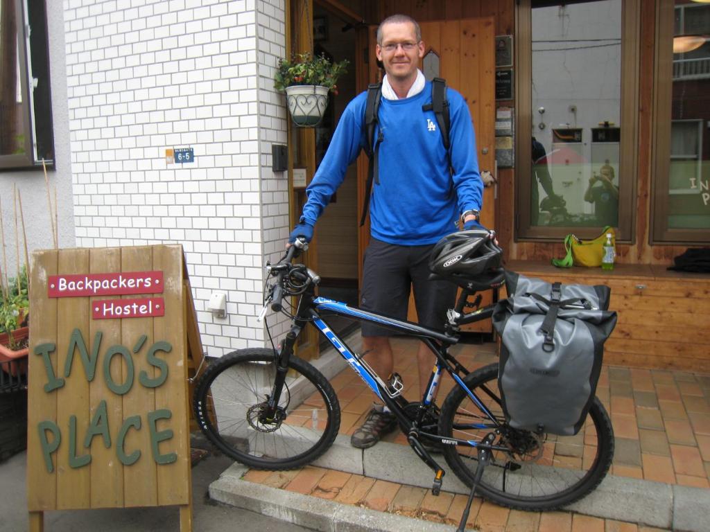 Ein Mann steht neben einem Fahrrad in der Unterkunft Backpackers Hostel Ino's Place in Sapporo