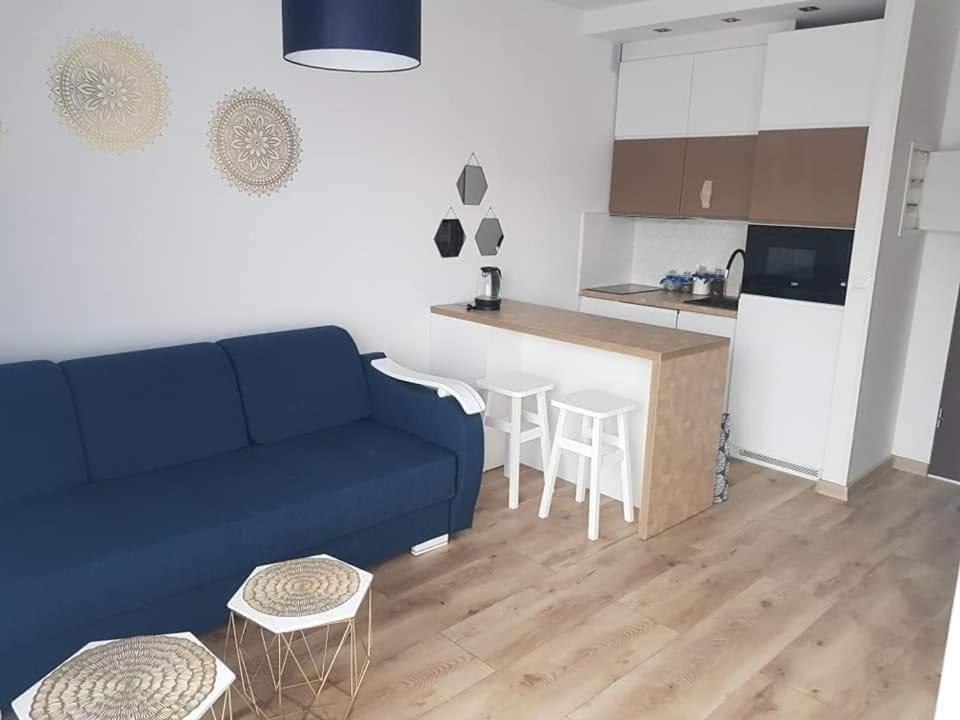 a living room with a blue couch and a kitchen at Apartament Północna in Darłowo