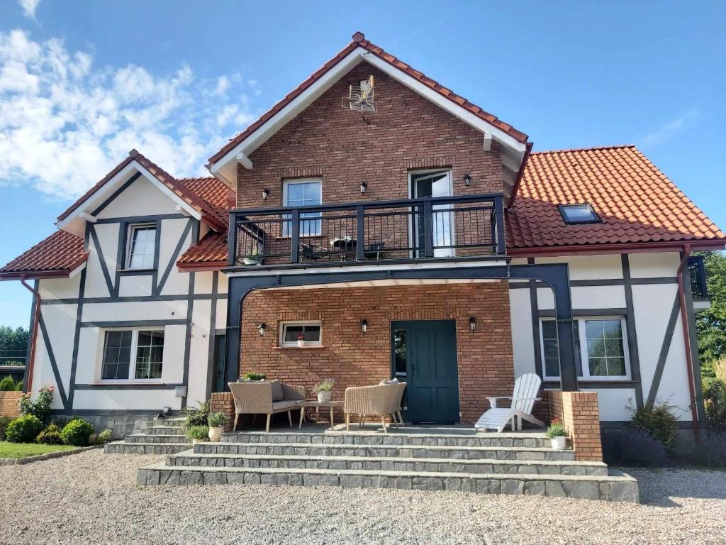 a house with a balcony on top of it at Domek na Błotach in Karwieńskie Błoto Drugie