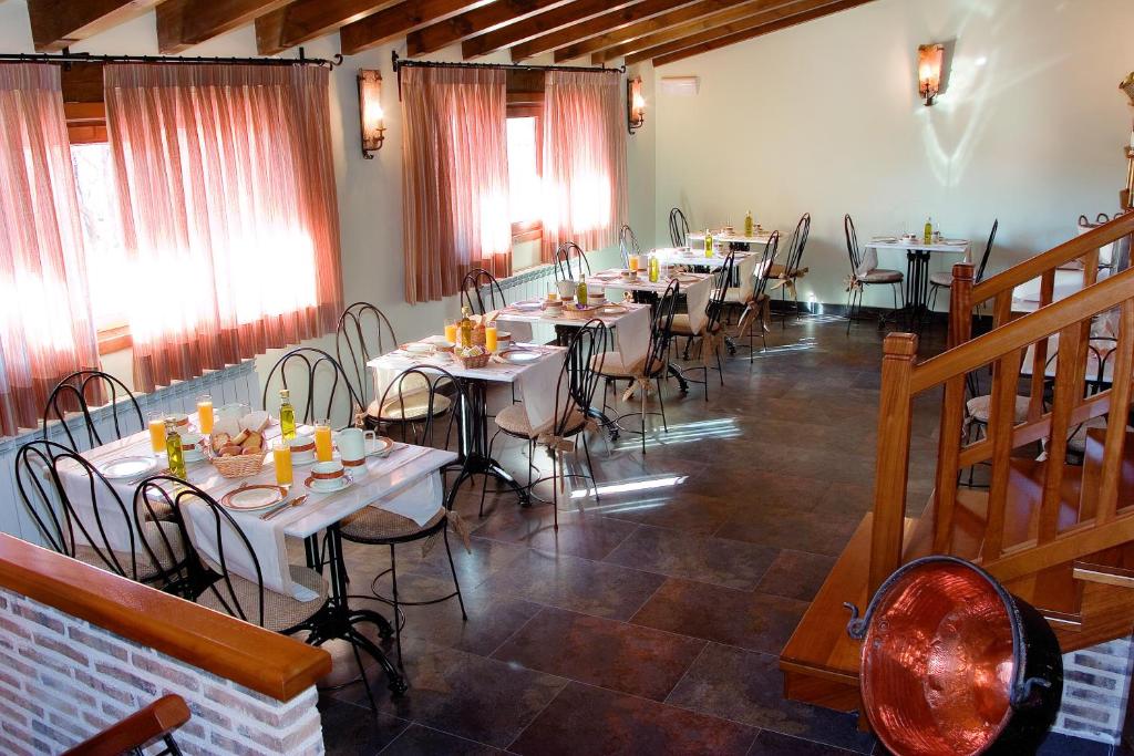 a dining room with tables and chairs and windows at Hotel Rural La Cabaña in Palazuelos